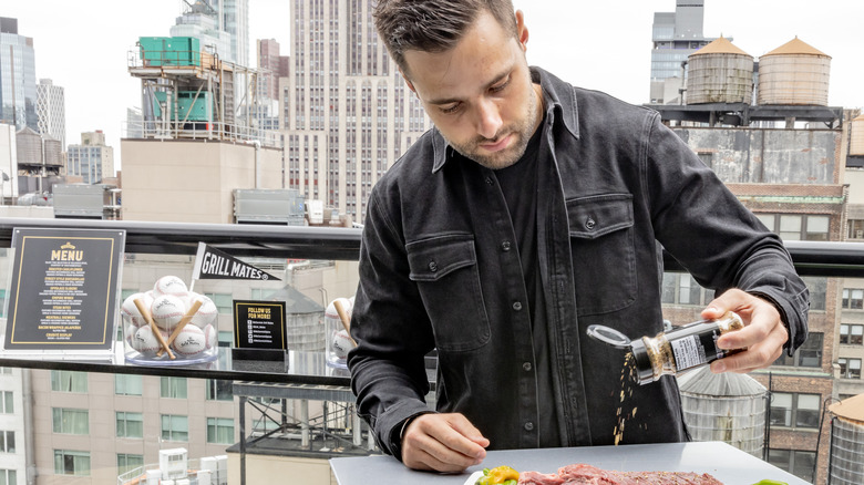 Max Greb sprinkling McCormick seasoning on meat