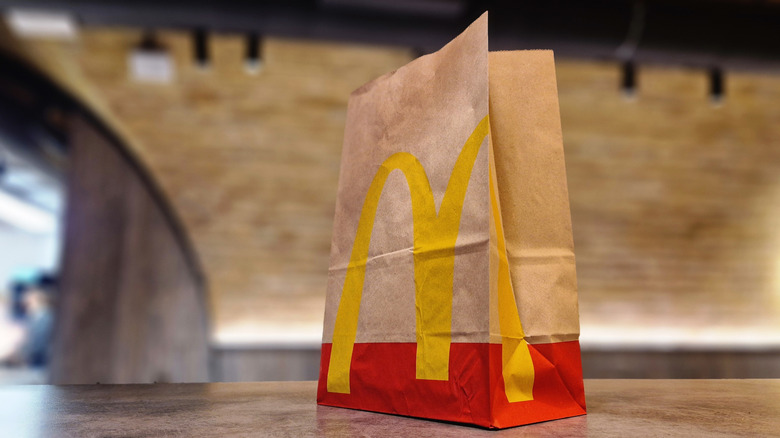 A brown and red McDonald's takeout bag on a brown table