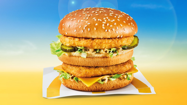 A Chicken Big Mac on a yellow and blue background with a lens flare behind it