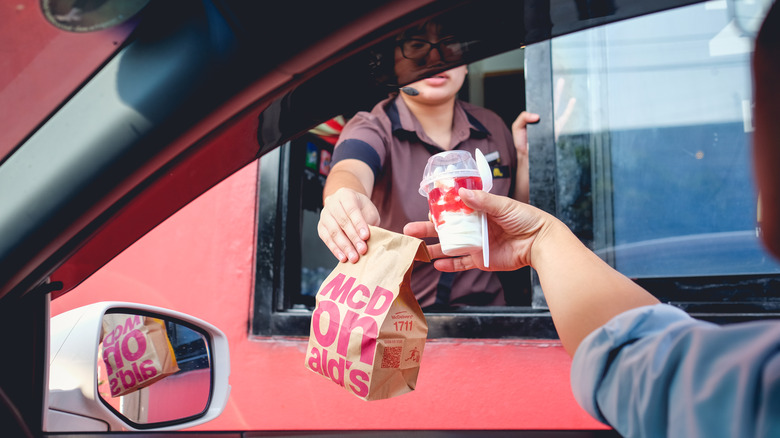 worker passes food at McDonald's drive-thru