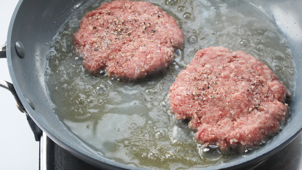 hamburger patties cooking in skillet