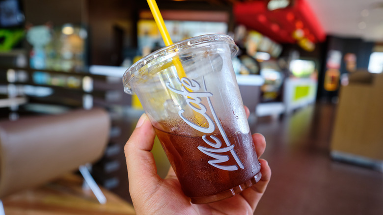 Hand holding half-full McDonald's iced coffee