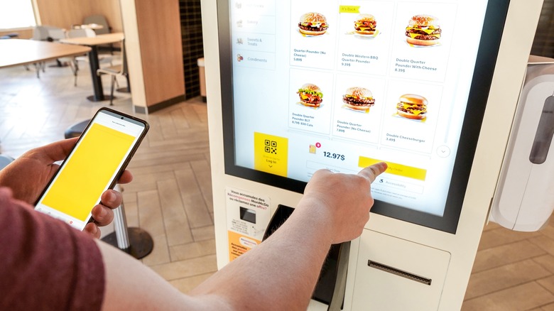 Person ordering food at a McDonald's touchscreen kiosk