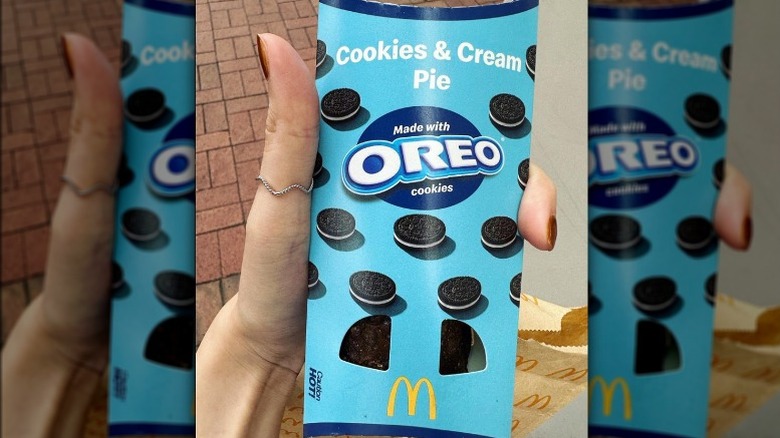 Hand holding Oreo cookies and cream pie in sleeve