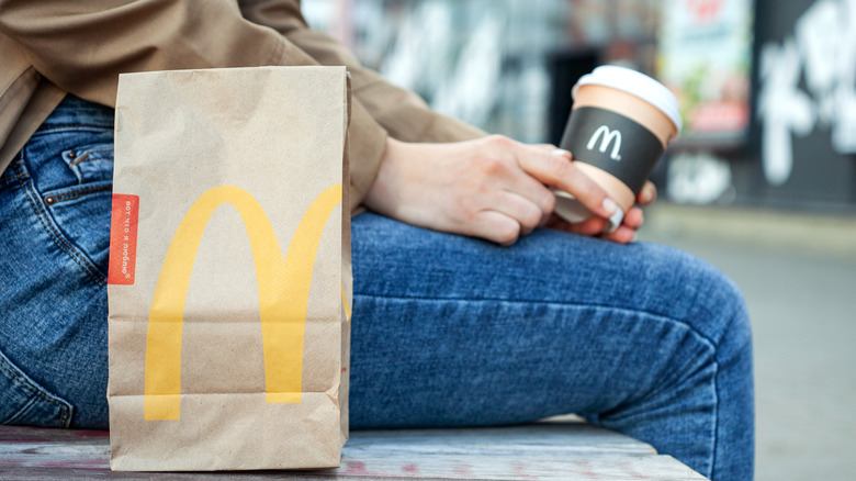 McDonald's bag next to someone holding a McDonald's coffee cup