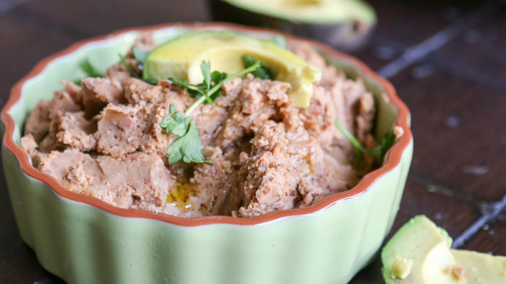Refried beans in light green bowl with cilantro