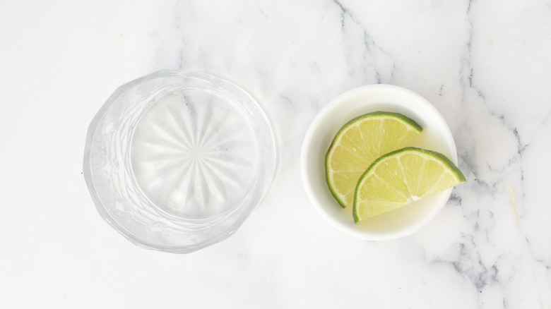 Cocktail glass next to bowl with lime slices