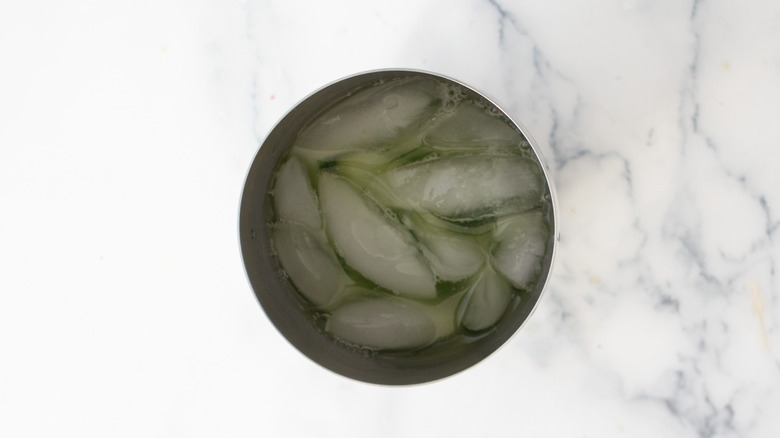 Cocktail shaker with ice and green liquid