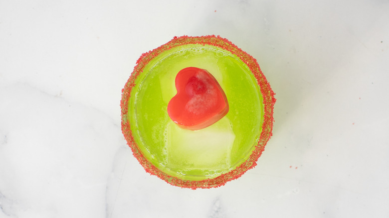 Top down view of green cocktail with heart ice cube