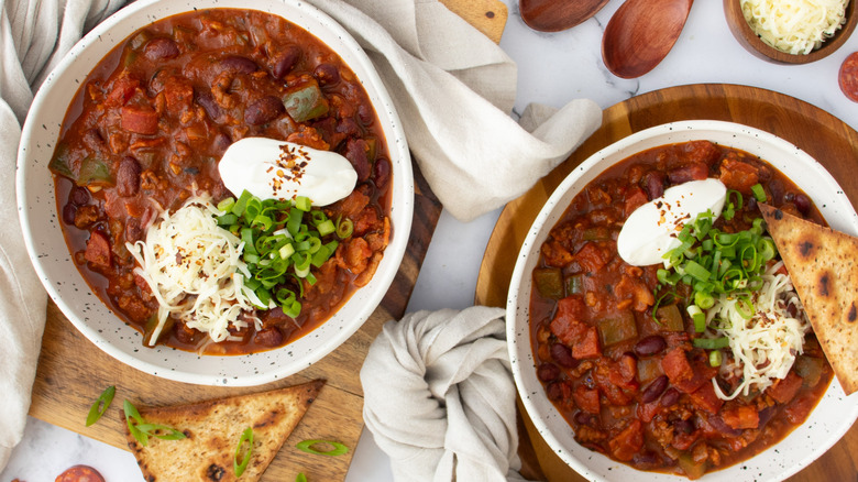 two meat chili bowls with toppings and bread