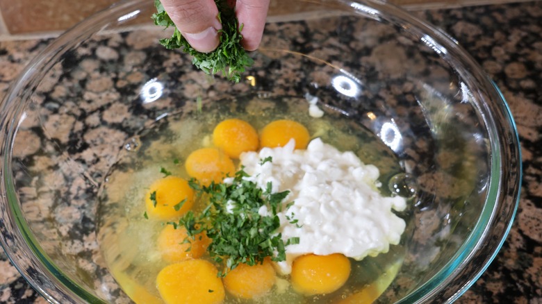 sprinkling parsley into bowl with eggs