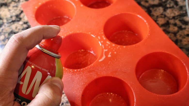 spraying cooking spray on muffin tin