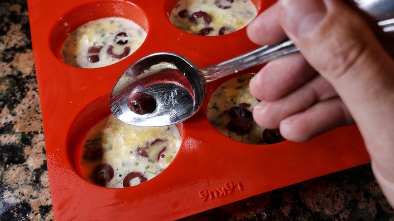 spooning olives into muffin tin