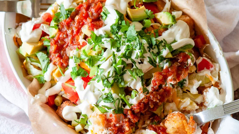 Tater tots layered with tomatoes, sour cream, and salsa