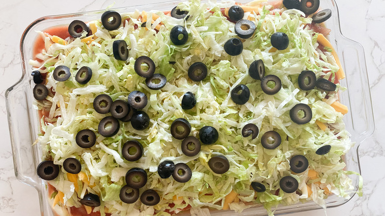 Baking dish with shredded lettuce and olives