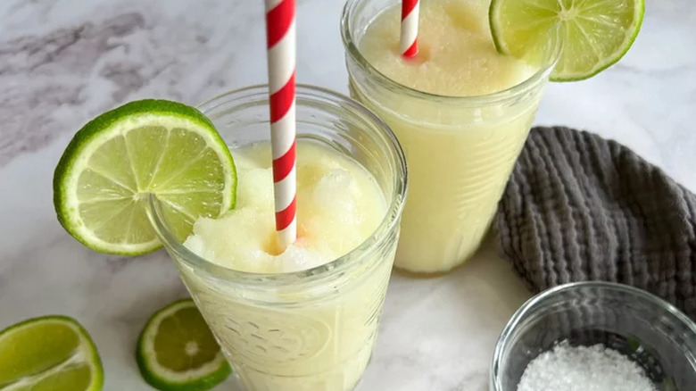 Two glasses with frozen cocktail and limes