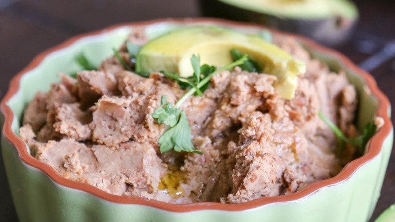 Bowl of refried beans with cilantro leaves