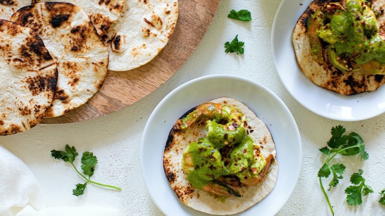 Chimichurri-topped tacos on white plates