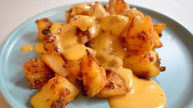 Fried potato cubes with cheese sauce