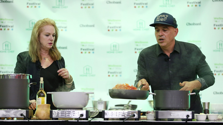 Michael Symon cooking onstage with a gray pan