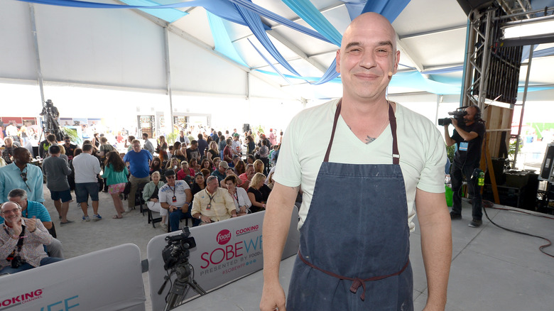 Michael Symon smiling in a blue apron