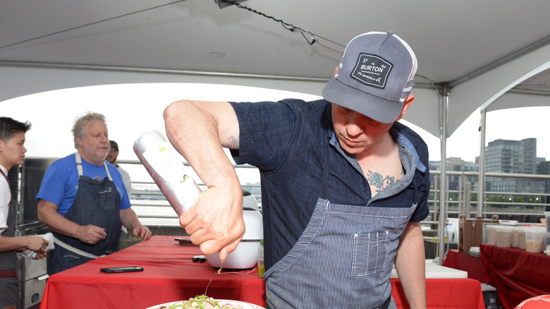 Michael Symon preparing a dish with oil