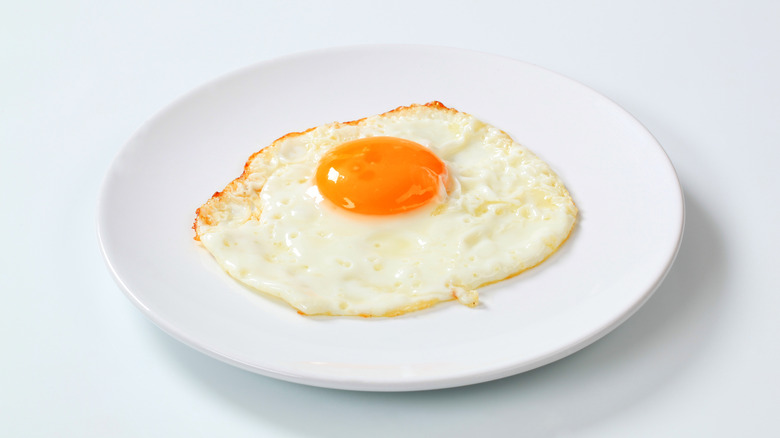 Sunny side up egg on a white plate on white background