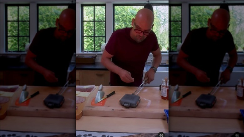 Michael symon holding a closed pie iron