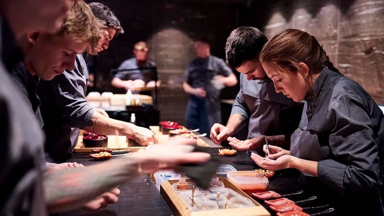 Multiple chefs preparing food in two rows