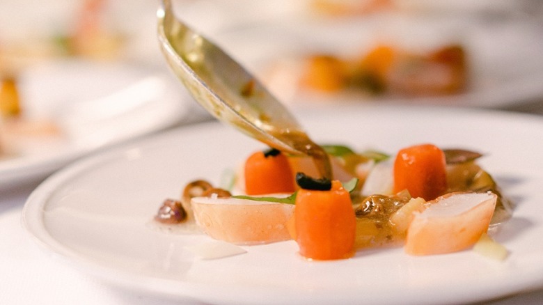 Close up of a spoon serving small bites of orange and white food