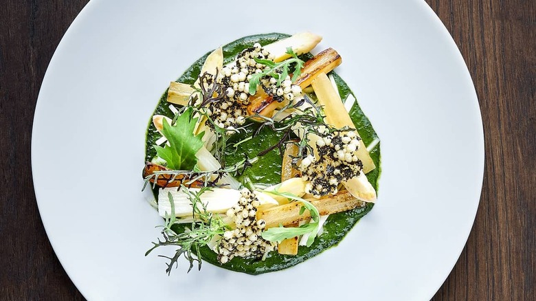 White plate with green and vegetable-rich food