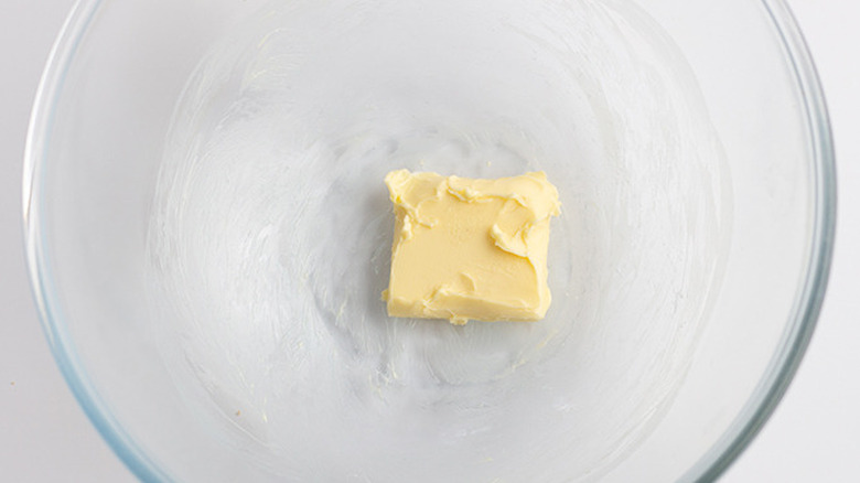 Overhead shot of a pat of butter in a glass mixing bowl