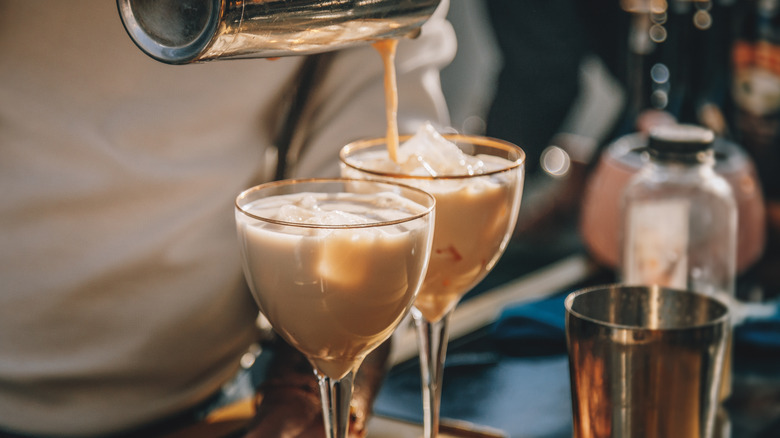 pouring milk liqueur into cocktail glasses