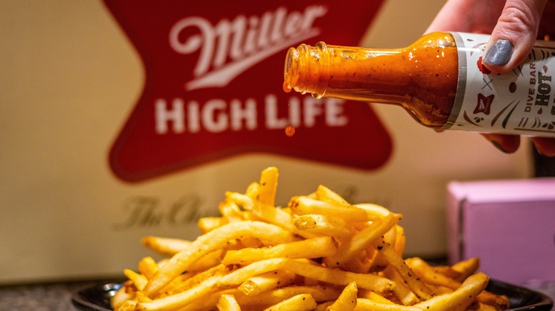 Hot sauce pouring onto fries 