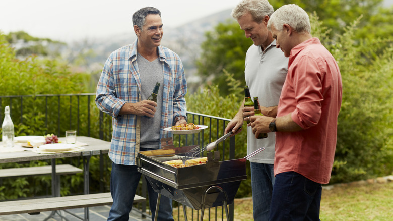 men grilling while drinking beers