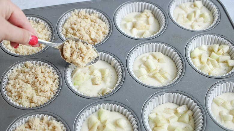 adding topping to mini cheesecakes