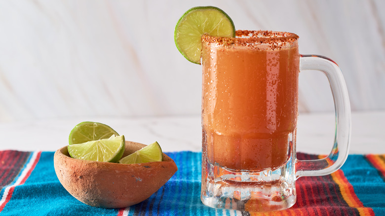 michelada in a mug with a bowl of limes 