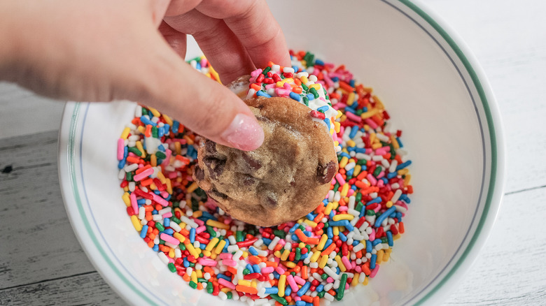 dipping cookie into rainbow sprinkles