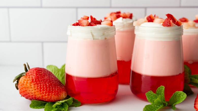 Mini jello parfaits sit beside strawberries