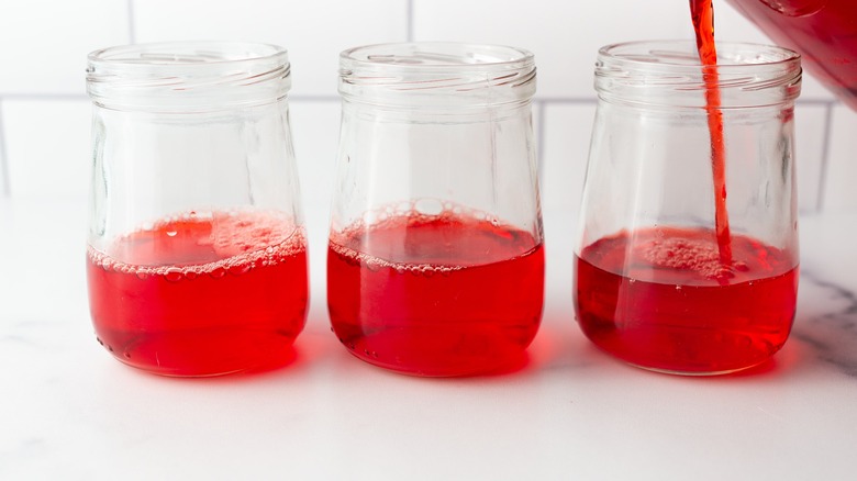 Red liquid pouring into small jars