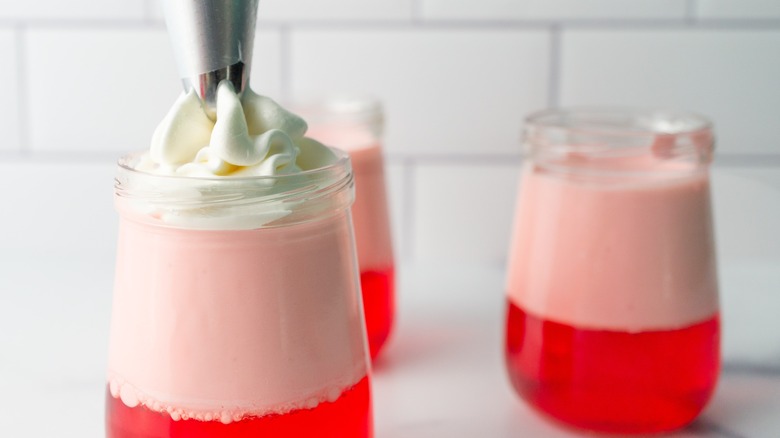 Cool whip being added to a jello parfait