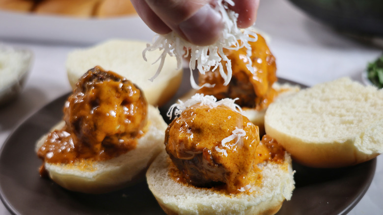 sprinkling Parmesan cheese on meatballs