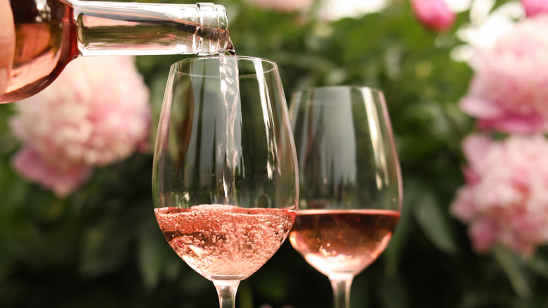 Bottle pouring rosé into wine glasses