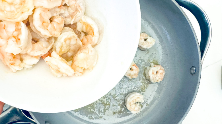 adding shrimp to frying pan