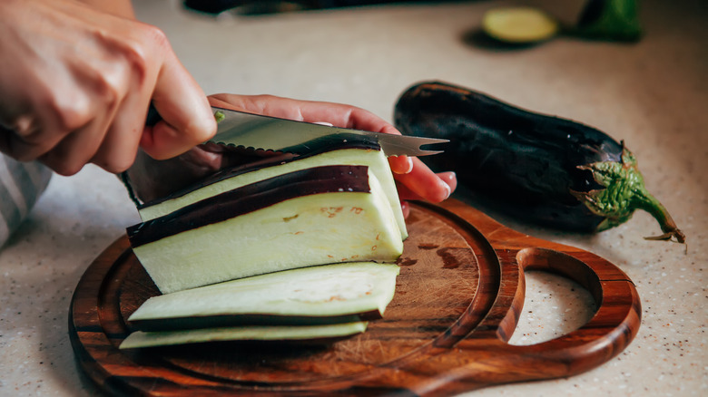 eggplant on wooden chopping board being cut