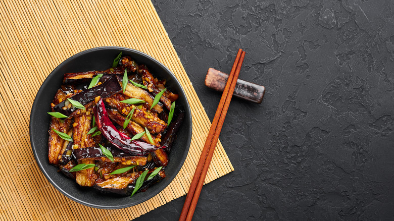 cooked eggplant in black bowl with chopsticks 