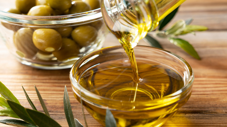 oil being poured into a glass jar on a wooden table