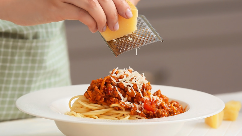 grating parmesan on pasta