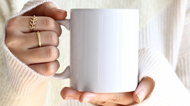 holding white coffee mug