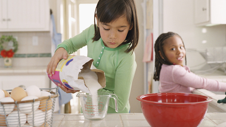 Kid pouring sugar in bowl